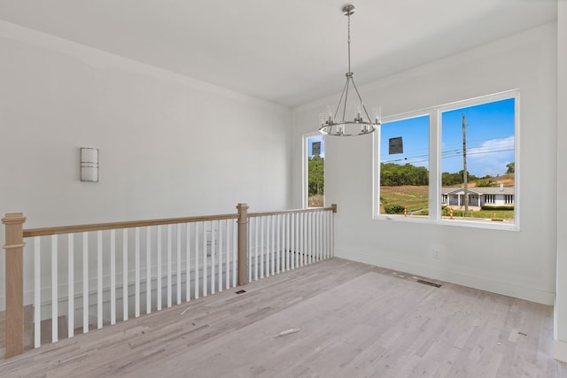 unfurnished room featuring light hardwood / wood-style flooring and a chandelier