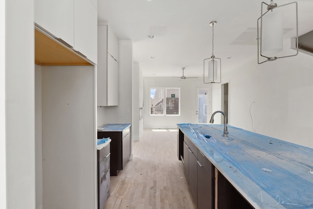 kitchen with white cabinets, light hardwood / wood-style floors, hanging light fixtures, and dark brown cabinetry