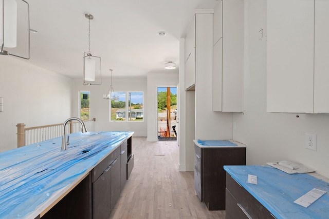 kitchen featuring white cabinets, light hardwood / wood-style flooring, pendant lighting, and dark brown cabinetry