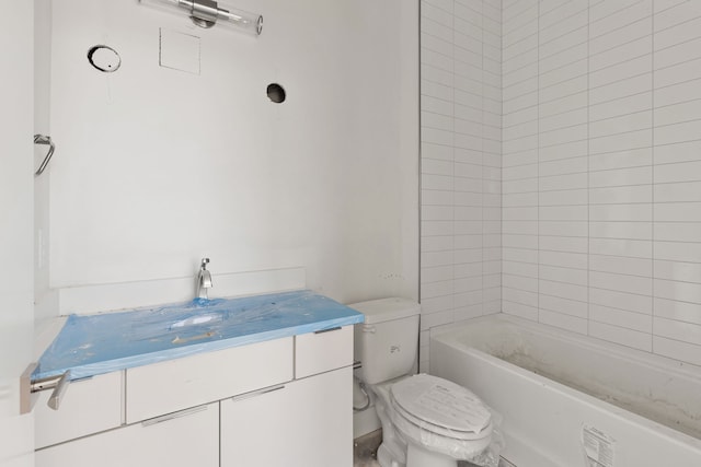 bathroom with vanity, a tub to relax in, and toilet