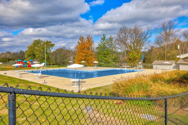 view of swimming pool featuring a diving board, a lawn, and a patio area