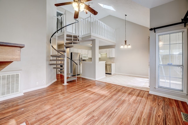 unfurnished living room with high vaulted ceiling, light hardwood / wood-style flooring, and ceiling fan with notable chandelier