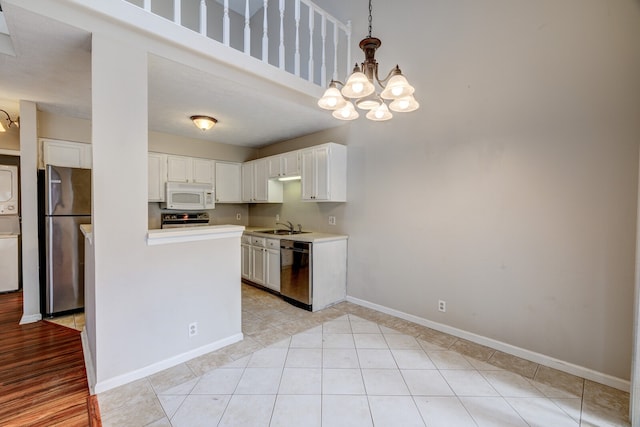 kitchen featuring sink, appliances with stainless steel finishes, light tile patterned floors, decorative light fixtures, and white cabinets