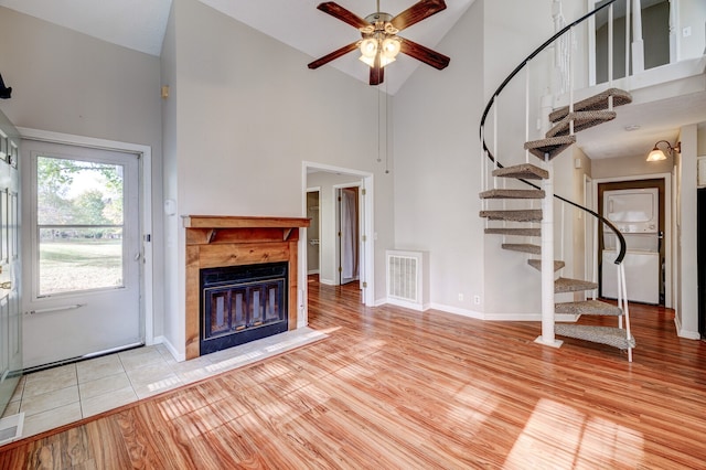 unfurnished living room with high vaulted ceiling, ceiling fan, and light hardwood / wood-style flooring