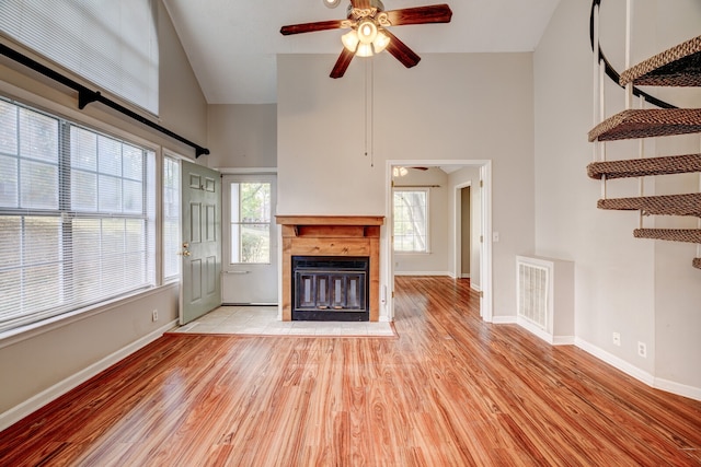 unfurnished living room with a wealth of natural light, light hardwood / wood-style floors, ceiling fan, and high vaulted ceiling