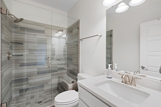 bathroom with a shower with door, vanity, and toilet