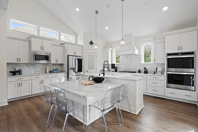 kitchen featuring white cabinetry, a center island with sink, appliances with stainless steel finishes, a kitchen bar, and pendant lighting