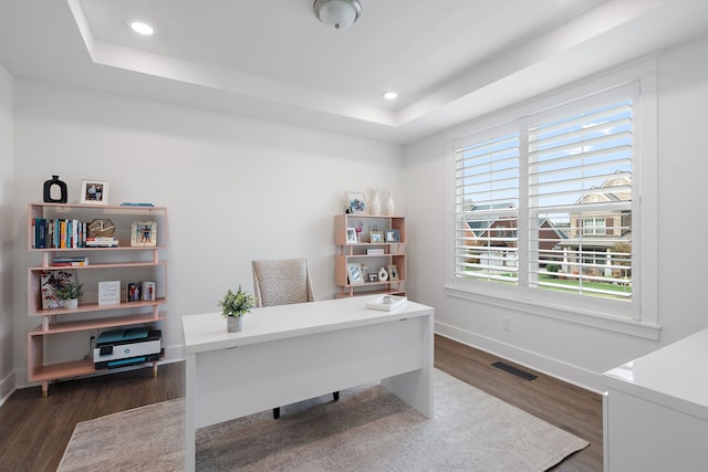 home office featuring dark hardwood / wood-style floors, a healthy amount of sunlight, and a tray ceiling