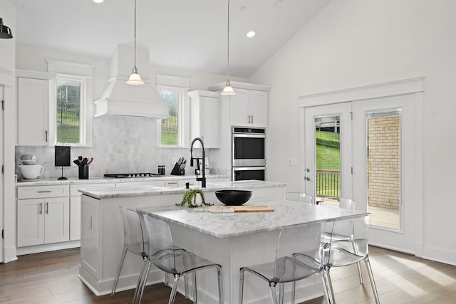 kitchen with stainless steel appliances, a large island, hanging light fixtures, a kitchen breakfast bar, and white cabinets