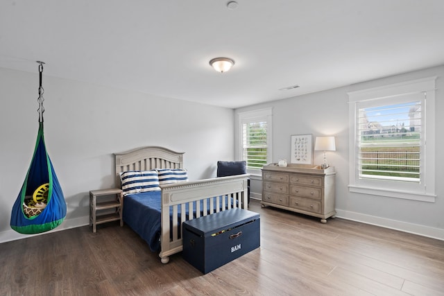 bedroom with hardwood / wood-style flooring and multiple windows