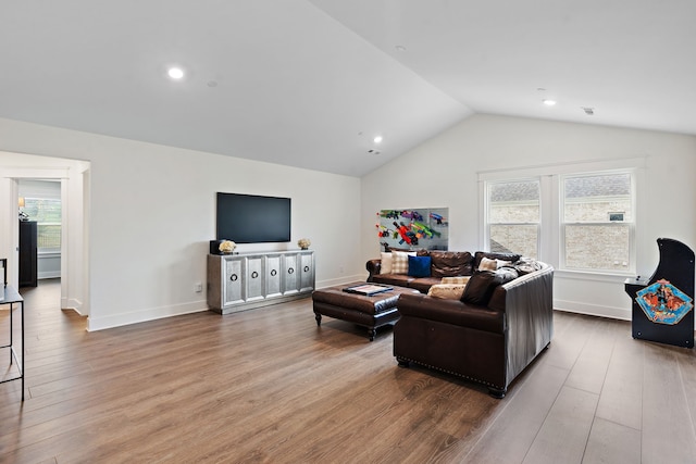 living room with wood-type flooring, a healthy amount of sunlight, and vaulted ceiling