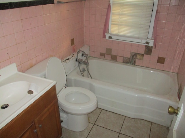 bathroom with tile walls, toilet, vanity, and tile patterned floors