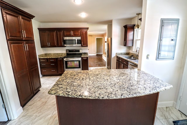 kitchen with decorative light fixtures, sink, electric panel, stainless steel appliances, and light stone countertops