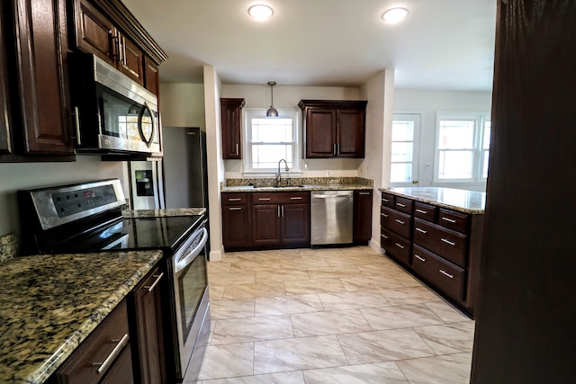 kitchen featuring dark brown cabinetry, sink, appliances with stainless steel finishes, pendant lighting, and light stone countertops