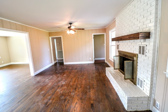 unfurnished living room with crown molding, dark wood-type flooring, ceiling fan, and a fireplace