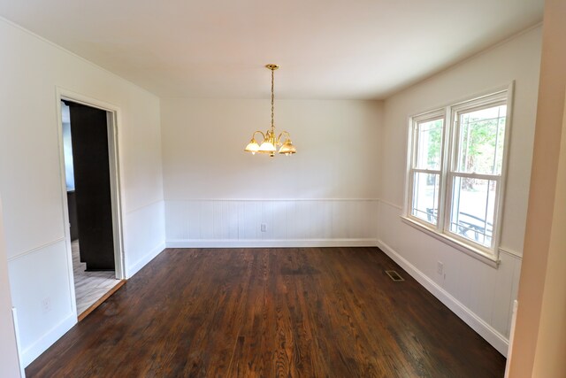 empty room with dark hardwood / wood-style flooring and a chandelier