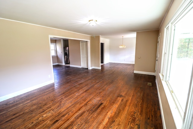 unfurnished room with dark hardwood / wood-style flooring, plenty of natural light, and an inviting chandelier