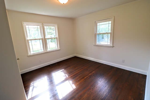 empty room with dark wood-type flooring and plenty of natural light