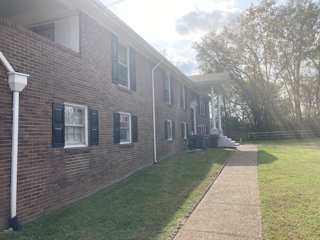 view of property exterior with central air condition unit and a yard