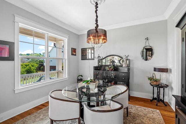 dining space featuring wood-type flooring, a healthy amount of sunlight, crown molding, and a notable chandelier