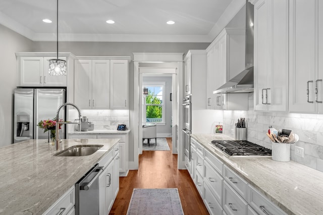 kitchen featuring wall chimney range hood, white cabinets, sink, and stainless steel appliances