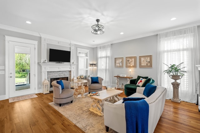 living room featuring a fireplace, light wood-type flooring, and ornamental molding