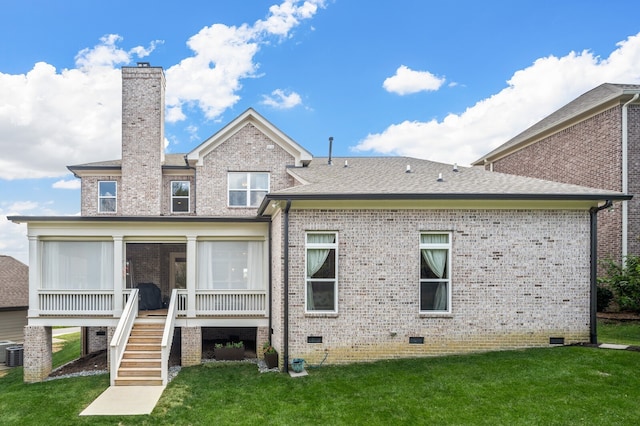 back of property with central air condition unit, a sunroom, and a yard