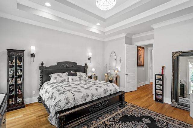 bedroom featuring ornamental molding, wood-type flooring, and a tray ceiling