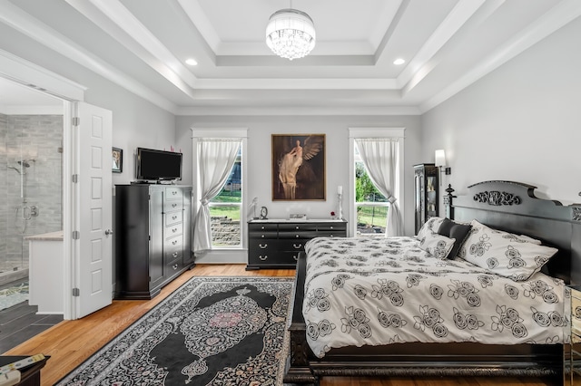 bedroom with hardwood / wood-style floors, access to exterior, multiple windows, and a raised ceiling