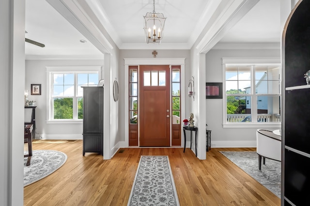 entrance foyer featuring ornamental molding, light hardwood / wood-style flooring, and a chandelier