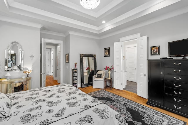 bedroom featuring wood-type flooring, crown molding, and a tray ceiling