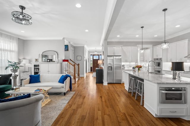 living room featuring sink, hardwood / wood-style flooring, and crown molding