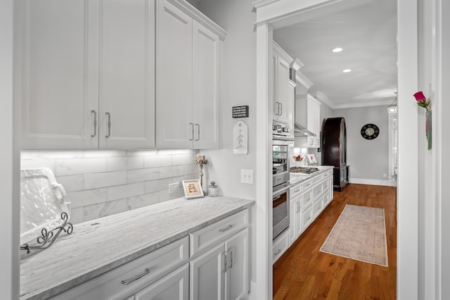 kitchen featuring tasteful backsplash, light stone counters, range hood, white cabinetry, and dark hardwood / wood-style flooring