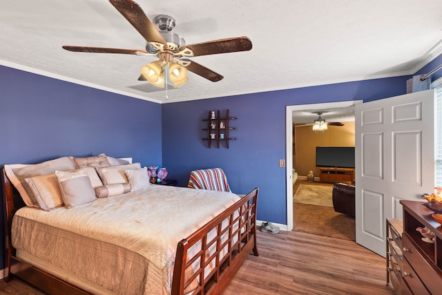 bedroom featuring hardwood / wood-style floors, ceiling fan, crown molding, and a textured ceiling