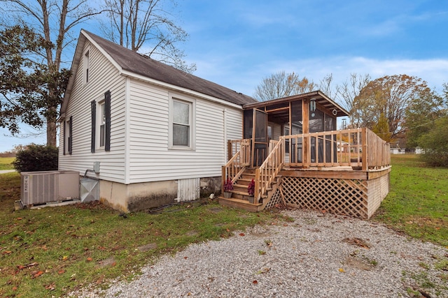 view of front of house featuring central AC, a sunroom, a front yard, and a deck