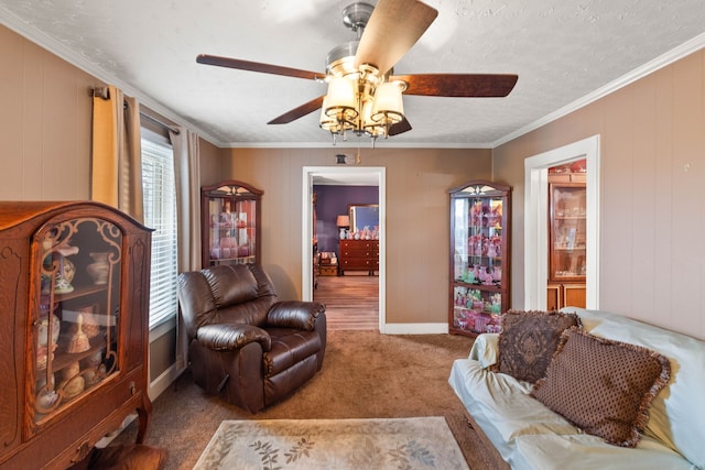 living room featuring carpet, a textured ceiling, ceiling fan, wooden walls, and crown molding