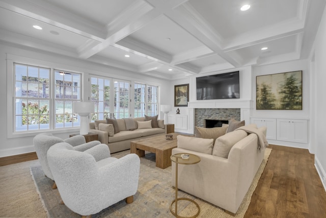 living room with a stone fireplace, wood-type flooring, and beamed ceiling