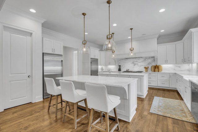 kitchen featuring a kitchen island, white cabinetry, appliances with stainless steel finishes, pendant lighting, and hardwood / wood-style floors