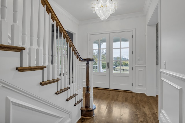 foyer with dark wood-type flooring, an inviting chandelier, french doors, and crown molding