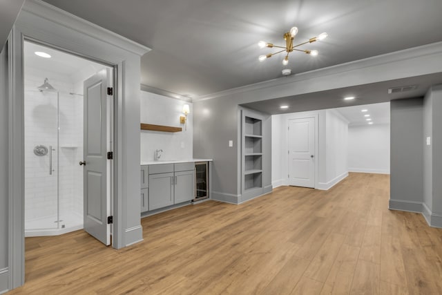 interior space featuring ornamental molding, indoor wet bar, beverage cooler, light hardwood / wood-style flooring, and built in features