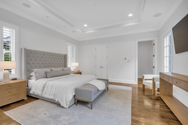 bedroom featuring a closet, hardwood / wood-style flooring, ornamental molding, and a raised ceiling