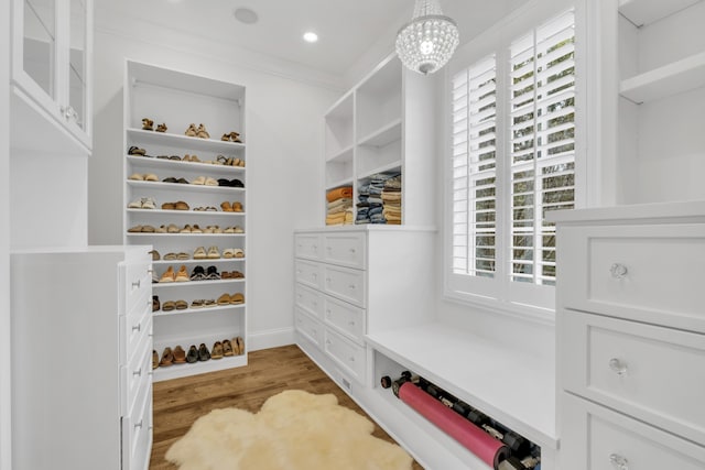 walk in closet featuring hardwood / wood-style flooring and an inviting chandelier