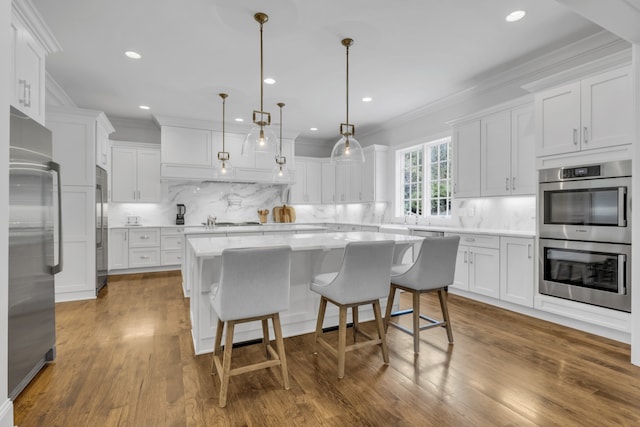 kitchen with white cabinets, stainless steel appliances, wood-type flooring, and a kitchen island