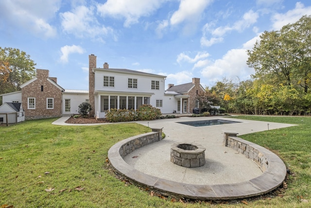 rear view of property with a storage shed, a fire pit, a lawn, and a patio area