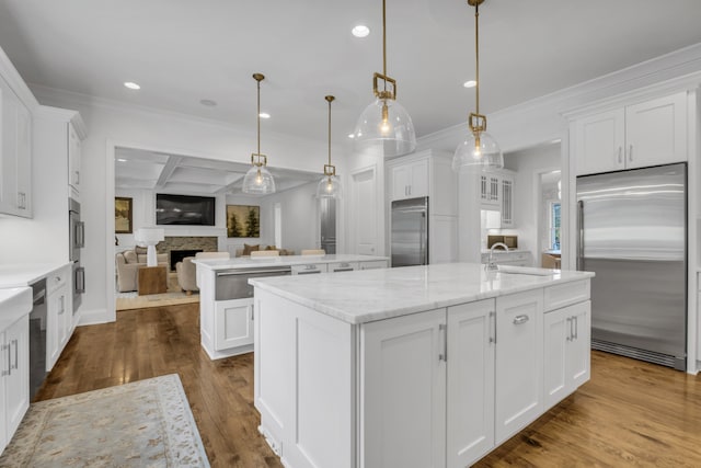 kitchen featuring an island with sink, white cabinetry, pendant lighting, and appliances with stainless steel finishes