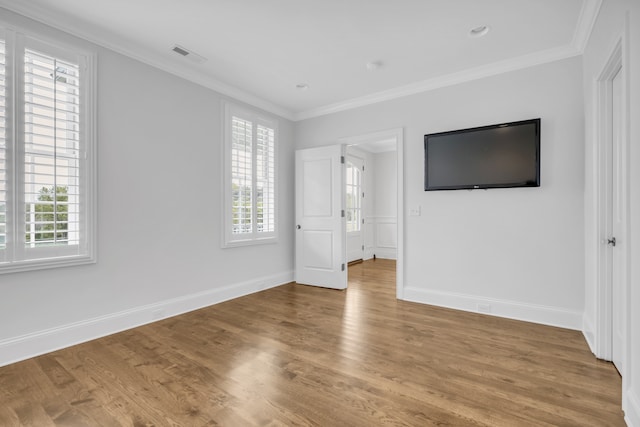 unfurnished bedroom with hardwood / wood-style flooring, multiple windows, and crown molding