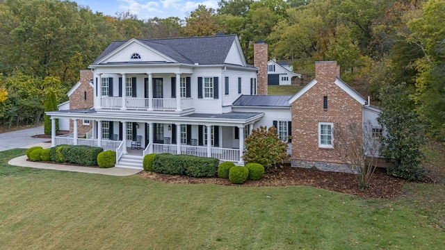 view of front of house with a front lawn, a balcony, and covered porch