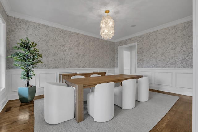 dining area featuring dark wood-type flooring, a notable chandelier, and ornamental molding