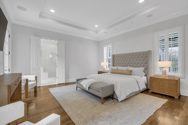 bedroom with ornamental molding, ensuite bath, a tray ceiling, and dark hardwood / wood-style flooring