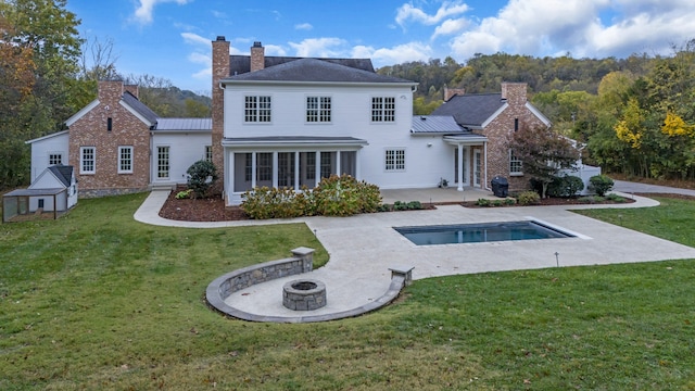 rear view of house with a shed, a fire pit, a lawn, and a patio